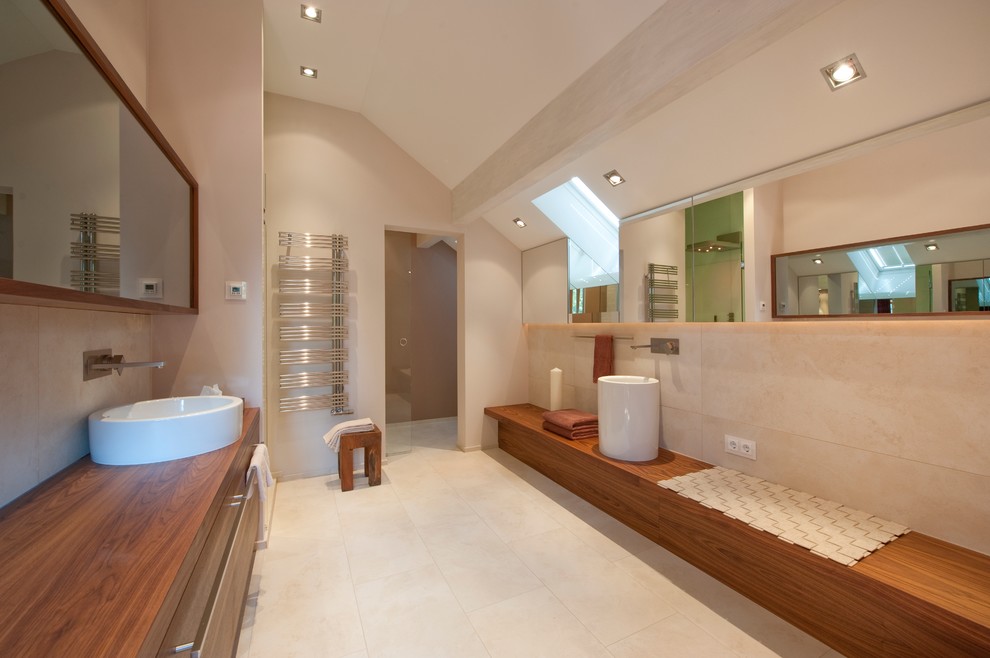 Photo of a mid-sized contemporary bathroom in Munich with beige walls, a vessel sink and wood benchtops.