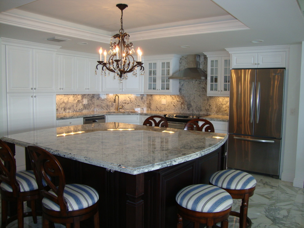 Photo of a large traditional l-shaped eat-in kitchen in Miami with an undermount sink, raised-panel cabinets, white cabinets, granite benchtops, grey splashback, stone slab splashback, stainless steel appliances, marble floors and with island.