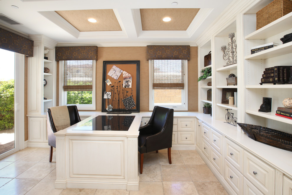 This is an example of a traditional home office in Orange County with a built-in desk and beige floor.