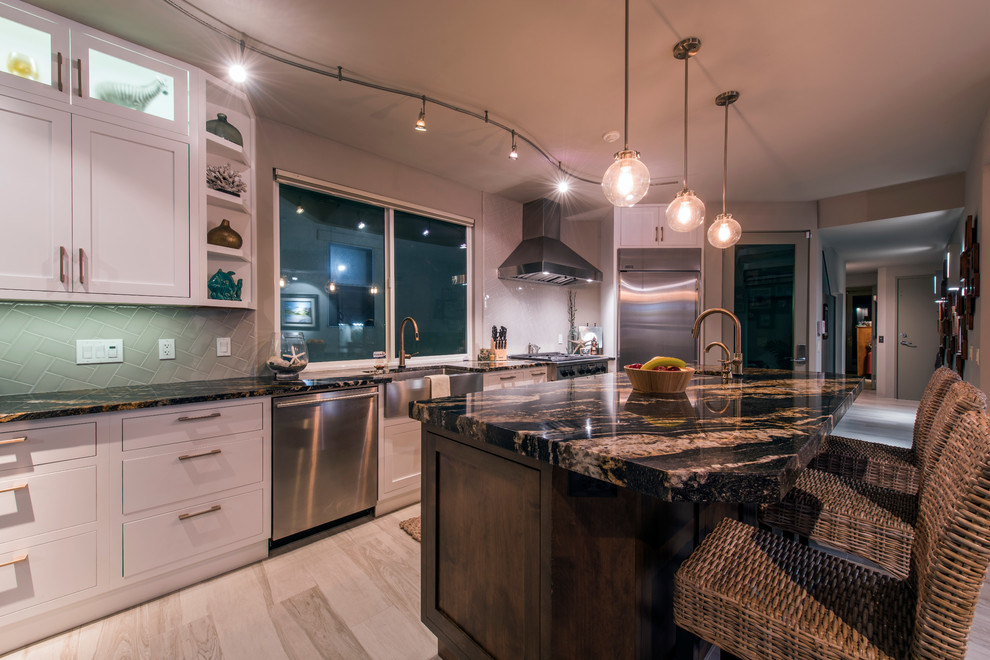 Inspiration for a mid-sized modern open plan kitchen in San Diego with a farmhouse sink, flat-panel cabinets, white cabinets, granite benchtops, grey splashback, subway tile splashback, stainless steel appliances, porcelain floors and with island.
