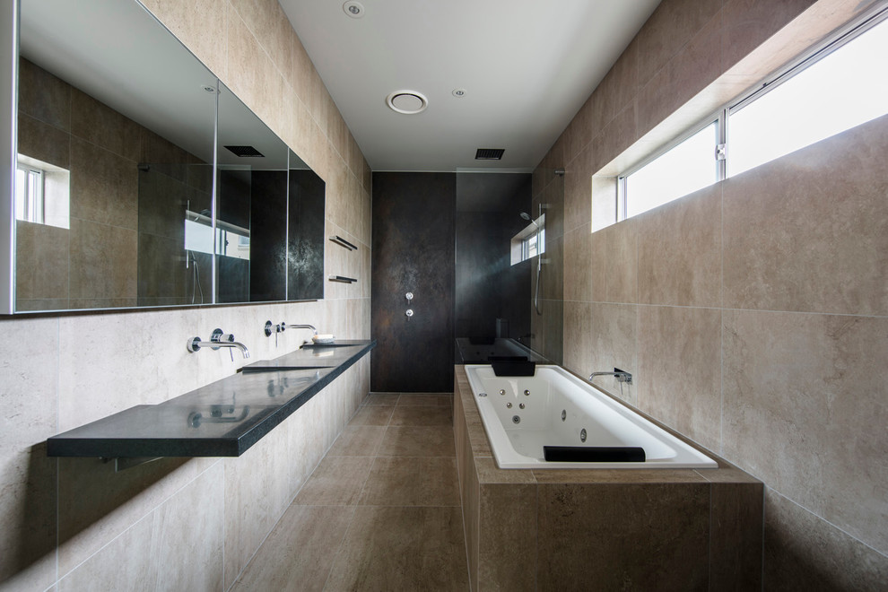 Photo of a contemporary bathroom in Sydney with an undermount tub, a two-piece toilet, beige tile, stone slab, beige walls, cement tiles, an integrated sink and onyx benchtops.