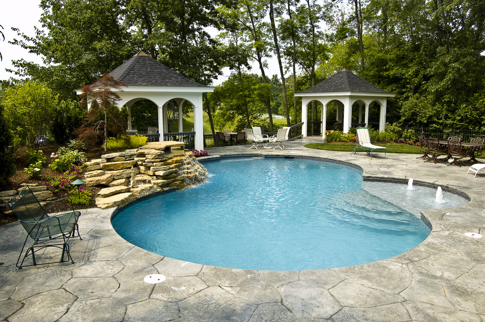 Inspiration for a mid-sized backyard custom-shaped natural pool in Cincinnati with stamped concrete.