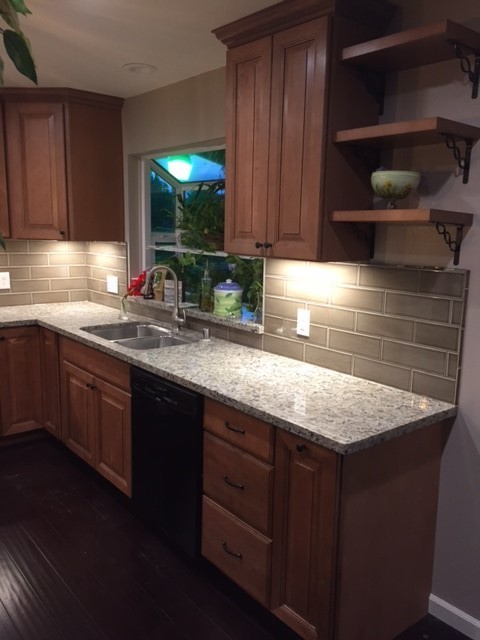 Mid-sized traditional l-shaped open plan kitchen in Sacramento with an undermount sink, raised-panel cabinets, medium wood cabinets, granite benchtops, grey splashback, porcelain splashback, stainless steel appliances, dark hardwood floors, with island and brown floor.