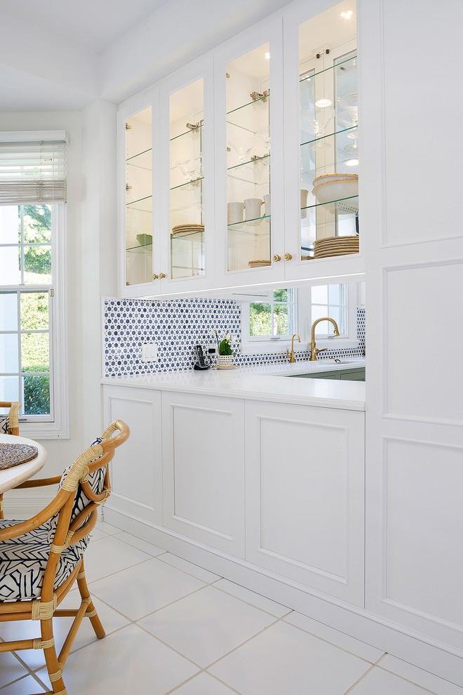 Mid-sized transitional l-shaped ceramic tile and beige floor open concept kitchen photo in Miami with an undermount sink, recessed-panel cabinets, white cabinets, solid surface countertops, multicolored backsplash, mosaic tile backsplash, stainless steel appliances, an island and white countertops