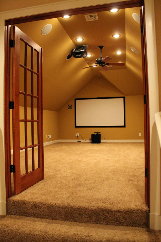 This is an example of a large traditional enclosed home theatre in Other with beige walls, carpet and a projector screen.
