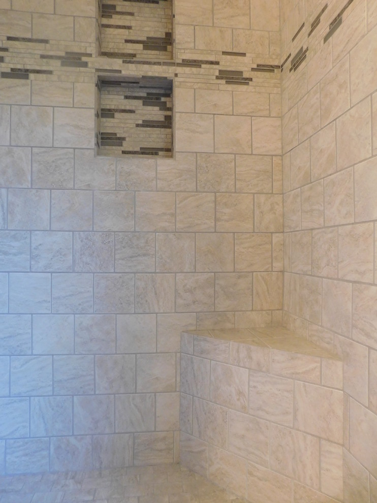 Example of a large transitional master gray tile and ceramic tile ceramic tile corner bathtub design with raised-panel cabinets, medium tone wood cabinets, a two-piece toilet, beige walls, an undermount sink and granite countertops