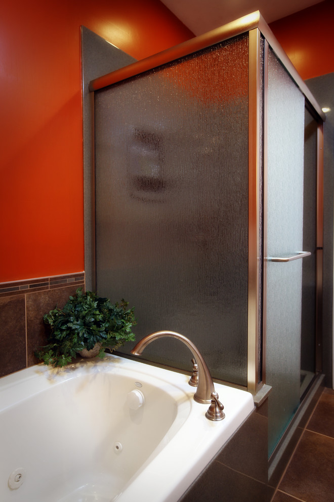 Mid-sized transitional kids bathroom in St Louis with an integrated sink, flat-panel cabinets, light wood cabinets, onyx benchtops, a drop-in tub, an alcove shower, a two-piece toilet, brown tile, porcelain tile, orange walls and porcelain floors.