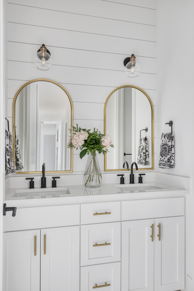 This is an example of a mid-sized country bathroom in Austin with shaker cabinets, white cabinets, a curbless shower, white tile, subway tile, white walls, an undermount sink, engineered quartz benchtops, white floor, a hinged shower door, white benchtops, a niche, a double vanity, a built-in vanity, planked wall panelling and ceramic floors.