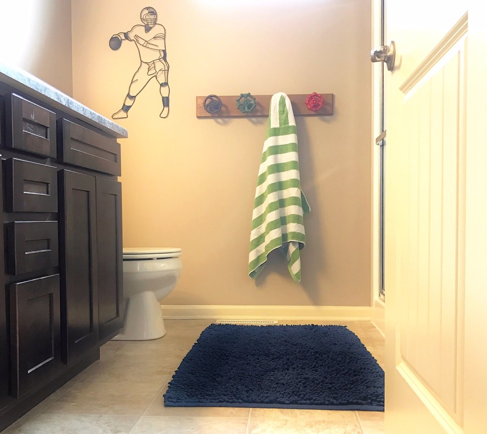 Photo of a mid-sized transitional kids bathroom in Omaha with shaker cabinets, dark wood cabinets, a one-piece toilet, brown walls, vinyl floors, laminate benchtops and beige floor.