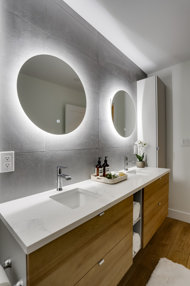 Design ideas for a mid-sized scandinavian bathroom in Vancouver with flat-panel cabinets, grey cabinets, an alcove tub, a shower/bathtub combo, gray tile, ceramic tile, white walls, vinyl floors, an undermount sink, quartzite benchtops, brown floor, white benchtops, a double vanity and a floating vanity.