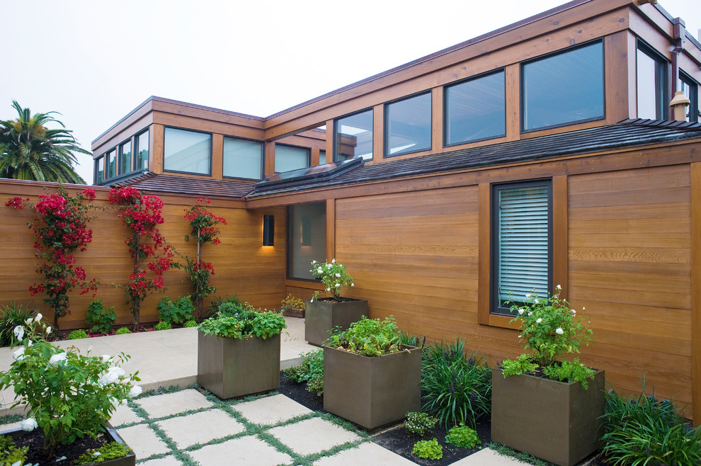 This is an example of a beach style exterior in San Francisco with wood siding and a flat roof.