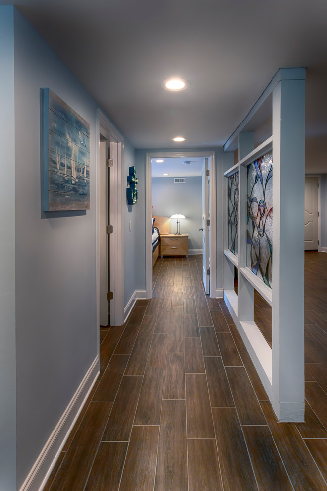 Large contemporary walk-out basement in Nashville with blue walls, ceramic floors, a standard fireplace, a stone fireplace surround and brown floor.