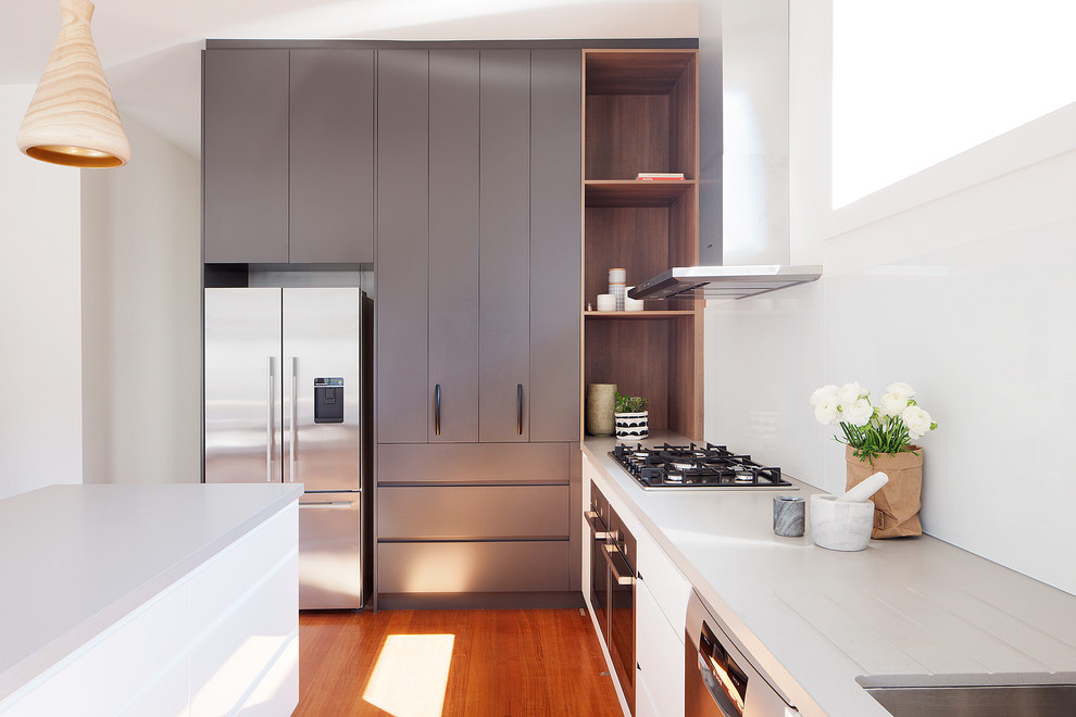 Inspiration for a large contemporary l-shaped eat-in kitchen in Melbourne with an undermount sink, flat-panel cabinets, black cabinets, white splashback, stainless steel appliances, medium hardwood floors and with island.
