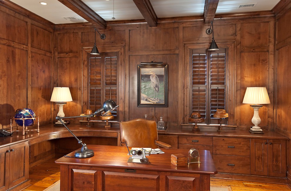 This is an example of a large traditional study room in Charleston with brown walls, a freestanding desk and brown floor.