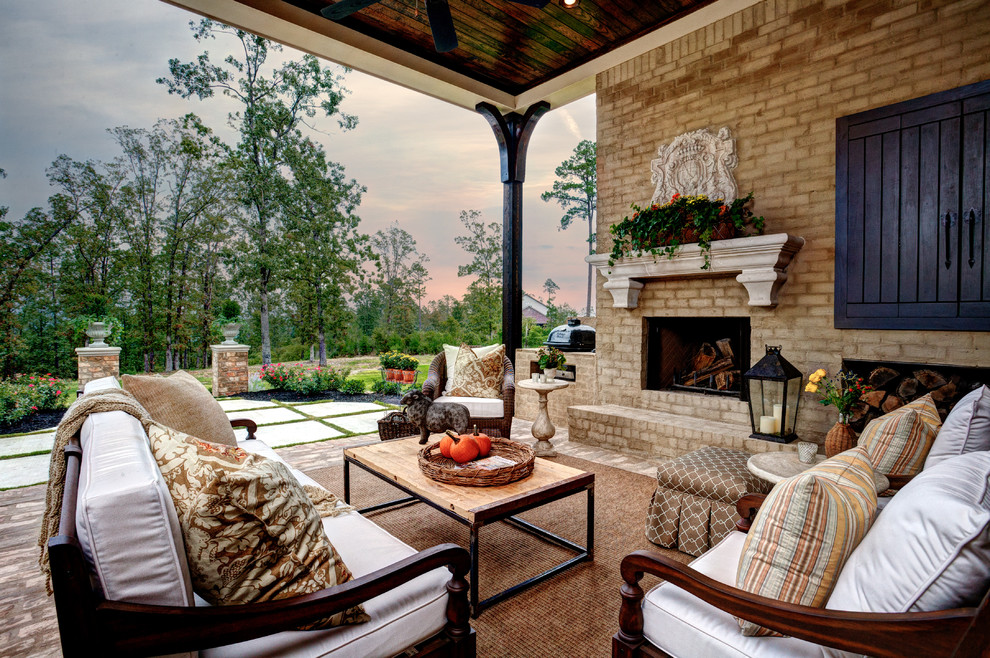 Photo of a large backyard patio in Little Rock with brick pavers, a roof extension and with fireplace.