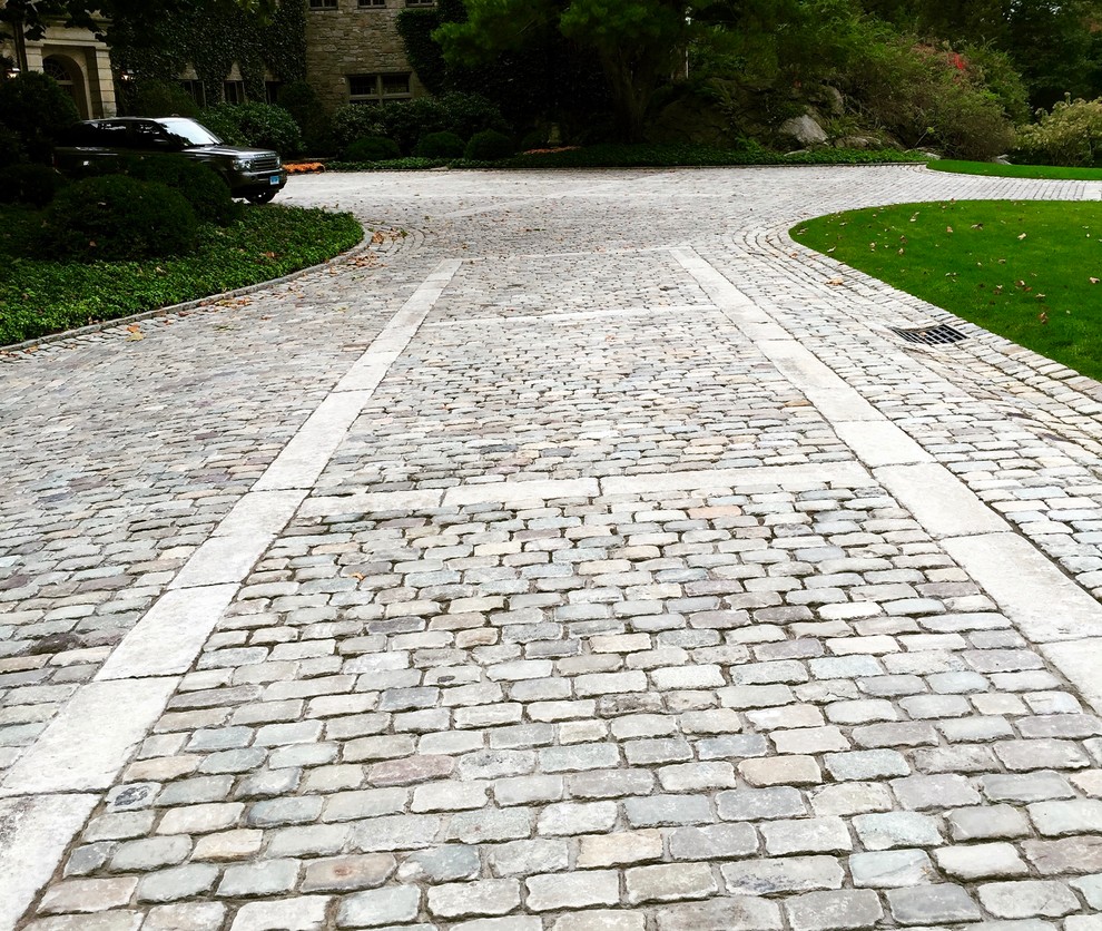 Photo of an expansive traditional courtyard driveway in New York with natural stone pavers.