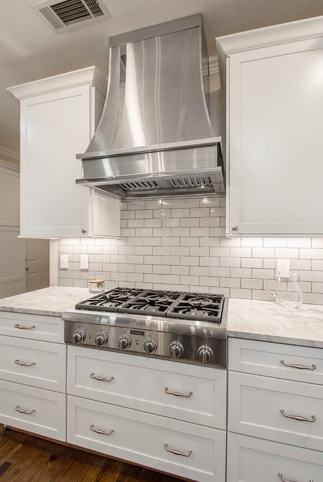Open concept kitchen - large transitional u-shaped medium tone wood floor open concept kitchen idea in Dallas with an undermount sink, shaker cabinets, white cabinets, quartz countertops, white backsplash, porcelain backsplash, stainless steel appliances and an island