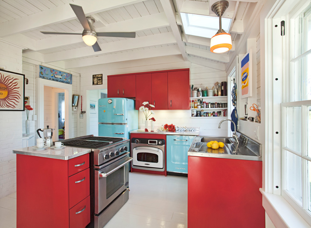 Photo of a beach style l-shaped kitchen in Boston with flat-panel cabinets, red cabinets, stainless steel benchtops and coloured appliances.