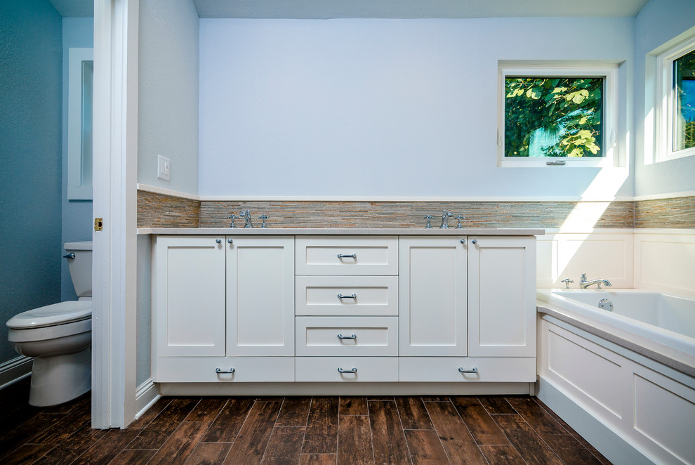 Drop-in bathtub - large transitional master beige tile and porcelain tile porcelain tile and brown floor drop-in bathtub idea with shaker cabinets, white cabinets, a one-piece toilet, blue walls, an undermount sink, quartz countertops and a hinged shower door