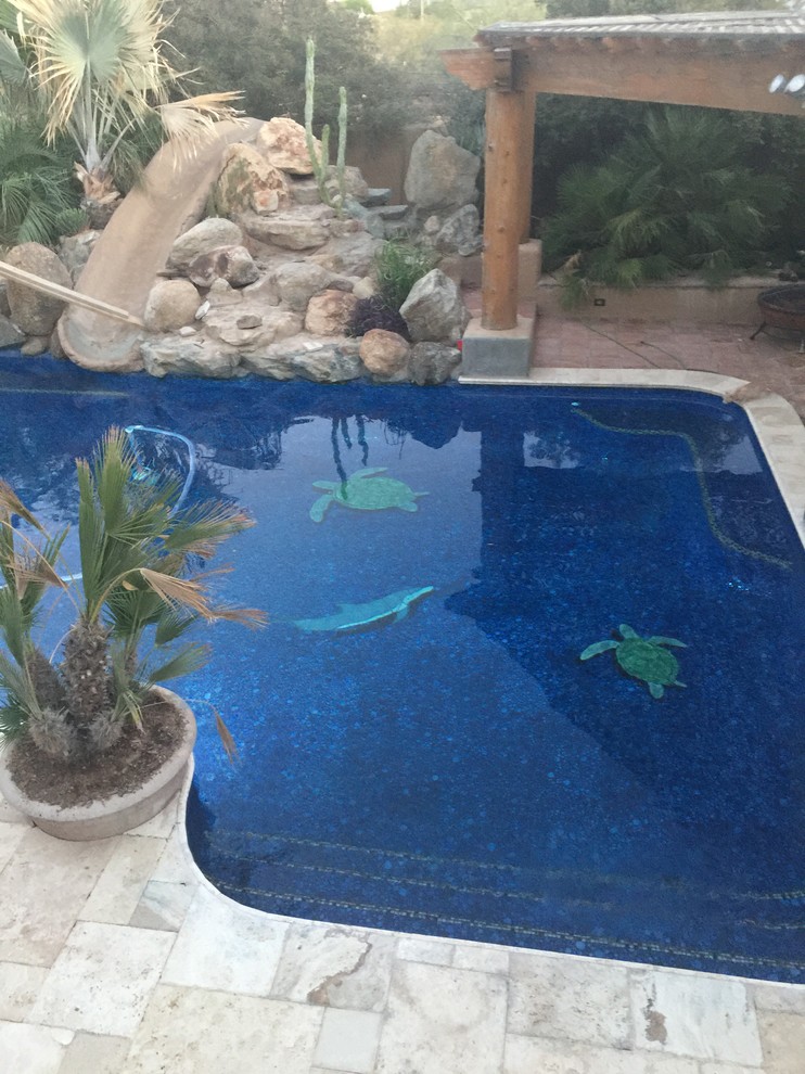 Photo of a mid-sized backyard custom-shaped natural pool in Phoenix with a water slide and natural stone pavers.