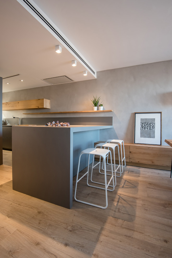 Photo of a large contemporary open plan dining in Barcelona with grey walls, laminate floors, a two-sided fireplace, a metal fireplace surround and brown floor.