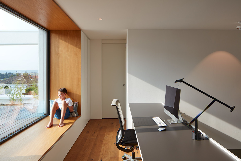Mittelgroßes Modernes Arbeitszimmer mit Studio, weißer Wandfarbe, hellem Holzboden, Einbau-Schreibtisch und braunem Boden in Stuttgart