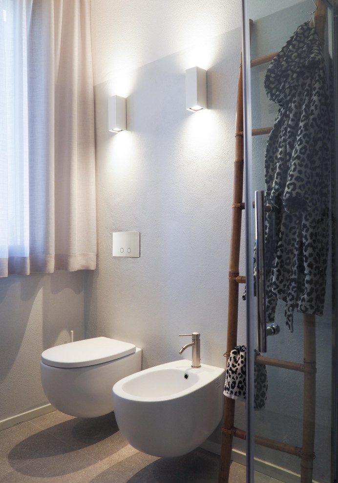 Источник вдохновения для домашнего уюта: ванная комната среднего размера в современном стиле с плоскими фасадами, светлыми деревянными фасадами, угловым душем, раздельным унитазом, серой плиткой, керамогранитной плиткой, серыми стенами, полом из керамогранита, душевой кабиной, монолитной раковиной, серым полом, душем с распашными дверями, серой столешницей, тумбой под одну раковину и подвесной тумбой
