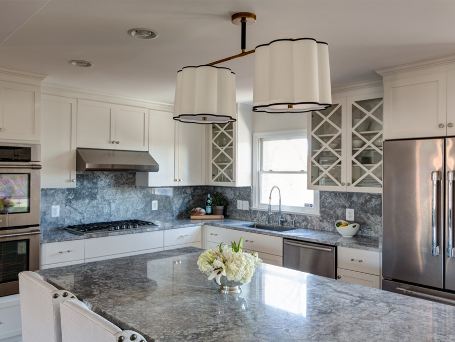 Large transitional light wood floor kitchen photo with an undermount sink, shaker cabinets, white cabinets, granite countertops, gray backsplash, stone slab backsplash, stainless steel appliances and an island