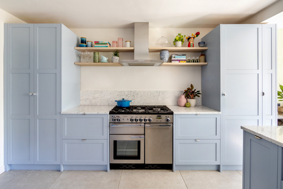 Imagen de cocina tradicional renovada cerrada con armarios estilo shaker, puertas de armario azules, electrodomésticos de acero inoxidable, suelo gris y encimeras blancas