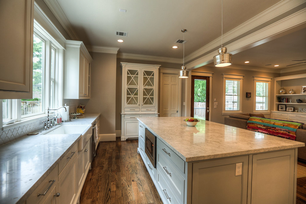 Design ideas for a large arts and crafts u-shaped kitchen in Houston with a farmhouse sink, shaker cabinets, white cabinets, marble benchtops, grey splashback, ceramic splashback, stainless steel appliances, medium hardwood floors and with island.