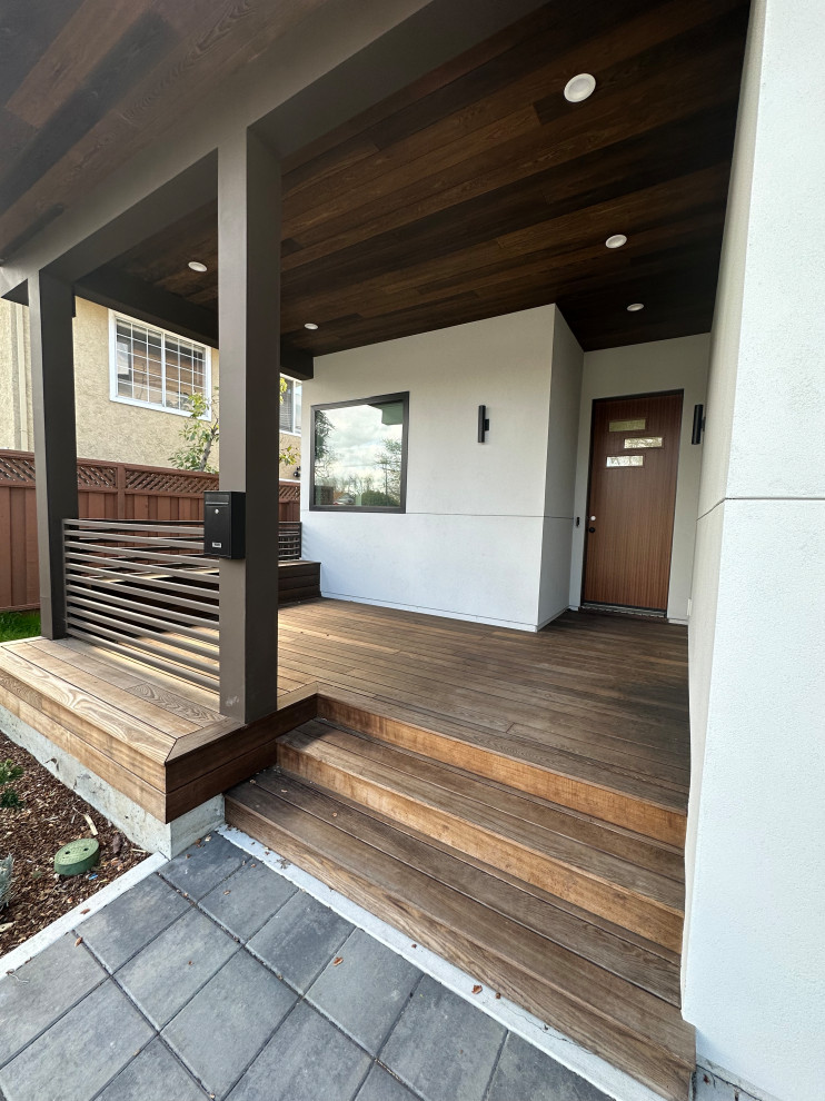 Inspiration for a large modern ground level deck in San Francisco with a roof extension and wood railing.