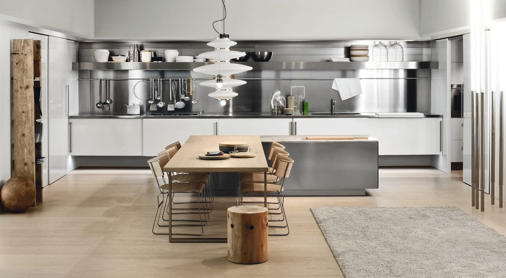 This is an example of a large contemporary single-wall eat-in kitchen in New York with an undermount sink, flat-panel cabinets, white cabinets, stainless steel benchtops, metallic splashback, metal splashback, stainless steel appliances, light hardwood floors, with island and beige floor.