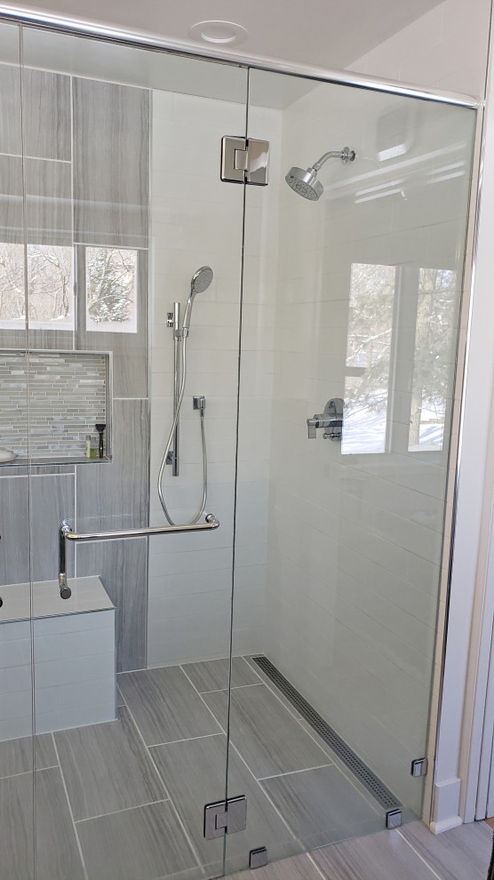 Example of a large transitional master gray tile and porcelain tile porcelain tile, gray floor and double-sink walk-in shower design with shaker cabinets, gray cabinets, a two-piece toilet, gray walls, an undermount sink, quartz countertops, a hinged shower door, white countertops, a niche and a built-in vanity