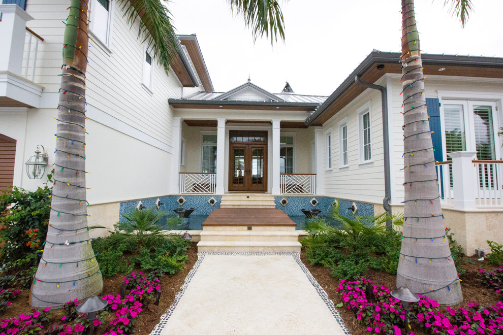 This is an example of a mid-sized tropical front door in Tampa with white walls, ceramic floors, a double front door, a glass front door and beige floor.