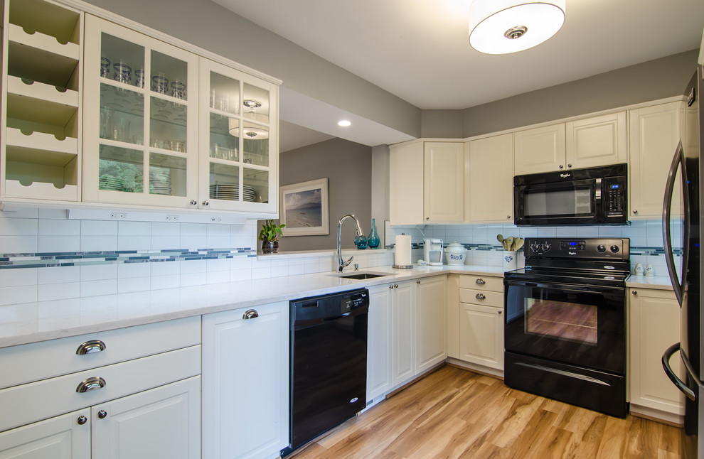 Example of a mid-sized transitional l-shaped vinyl floor enclosed kitchen design in DC Metro with an undermount sink, shaker cabinets, quartz countertops, white backsplash, ceramic backsplash, black appliances and no island