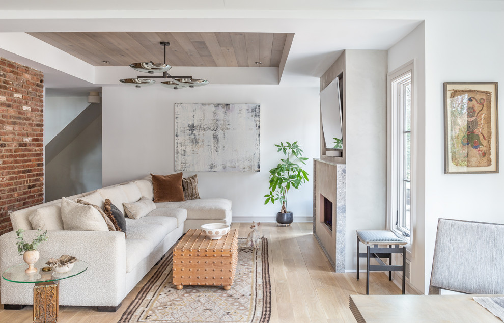 Ejemplo de sala de estar clásica renovada con paredes blancas, suelo de madera clara, pared multimedia, todas las chimeneas, bandeja, ladrillo, marco de chimenea de hormigón y suelo beige