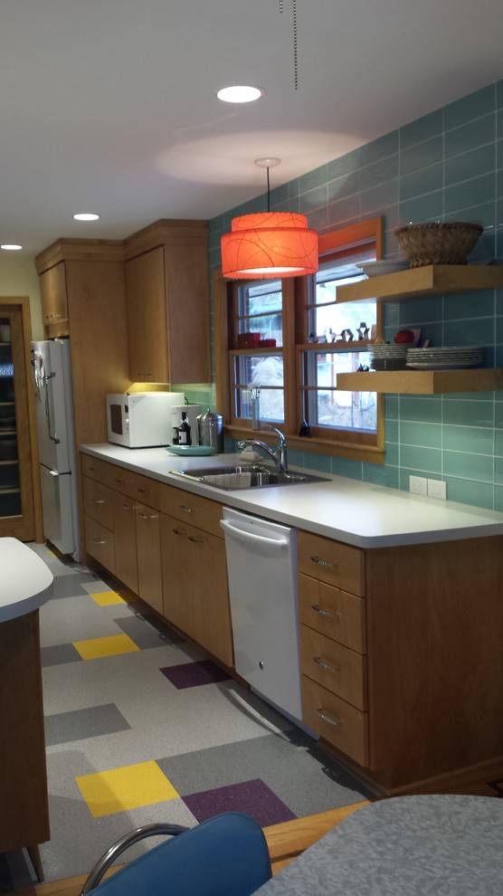 Mid-sized midcentury kitchen in Omaha with flat-panel cabinets, medium wood cabinets, laminate benchtops, green splashback, glass tile splashback, white appliances, vinyl floors and multi-coloured floor.