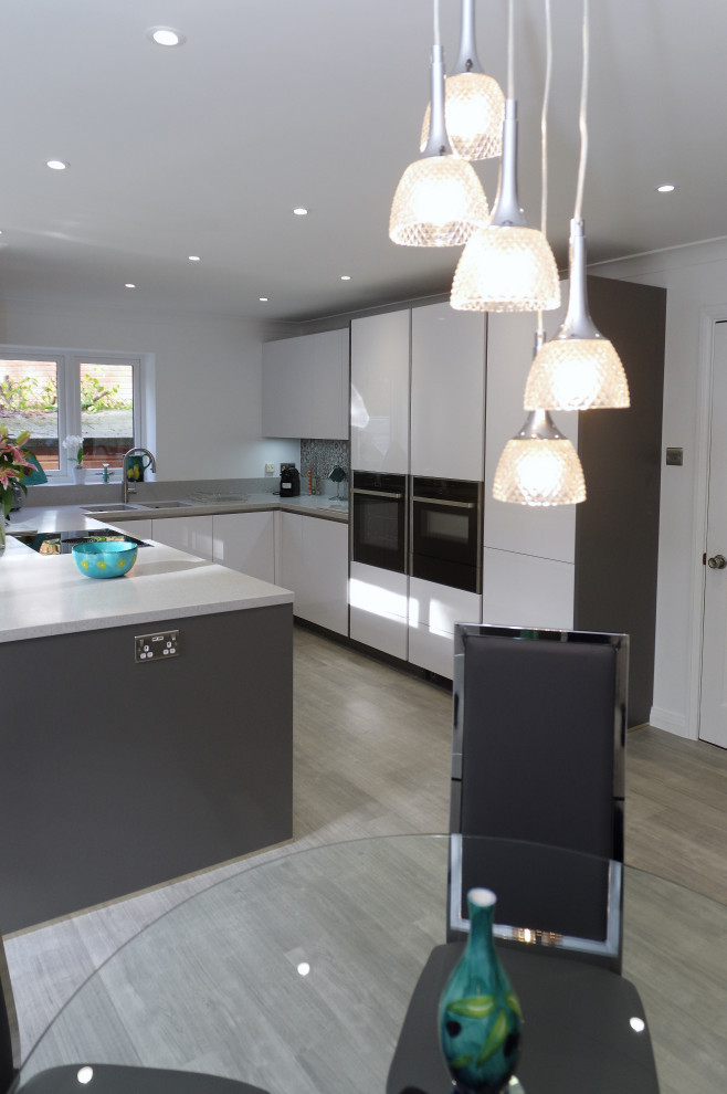Design ideas for a large contemporary eat-in kitchen in Kent with white cabinets, grey splashback, black appliances and grey benchtop.