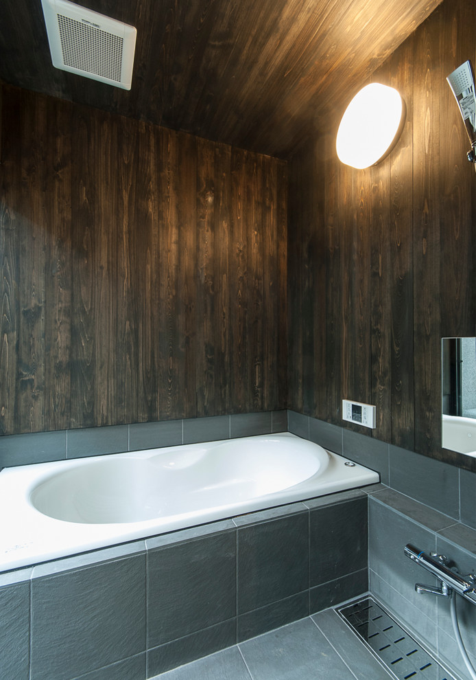 Design ideas for an asian bathroom in Tokyo with a drop-in tub, black tile and brown walls.