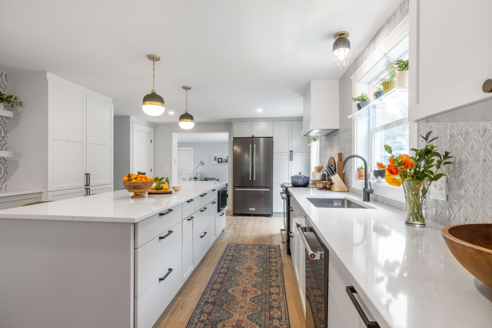 Inspiration for a medium sized traditional galley kitchen/diner in Portland Maine with a submerged sink, shaker cabinets, white cabinets, engineered stone countertops, blue splashback, porcelain splashback, stainless steel appliances, porcelain flooring, an island, brown floors and white worktops.