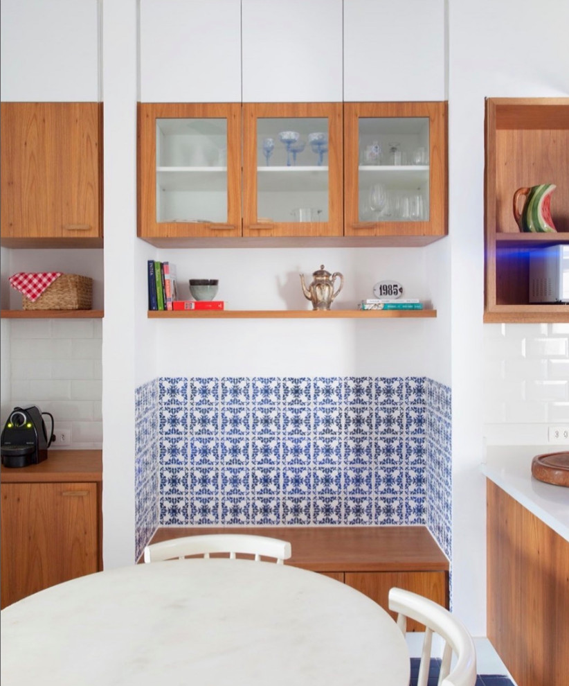 This is an example of a small midcentury l-shaped kitchen in Dallas with an undermount sink, flat-panel cabinets, medium wood cabinets, quartz benchtops, white splashback, ceramic splashback, stainless steel appliances, ceramic floors, with island, blue floor and white benchtop.