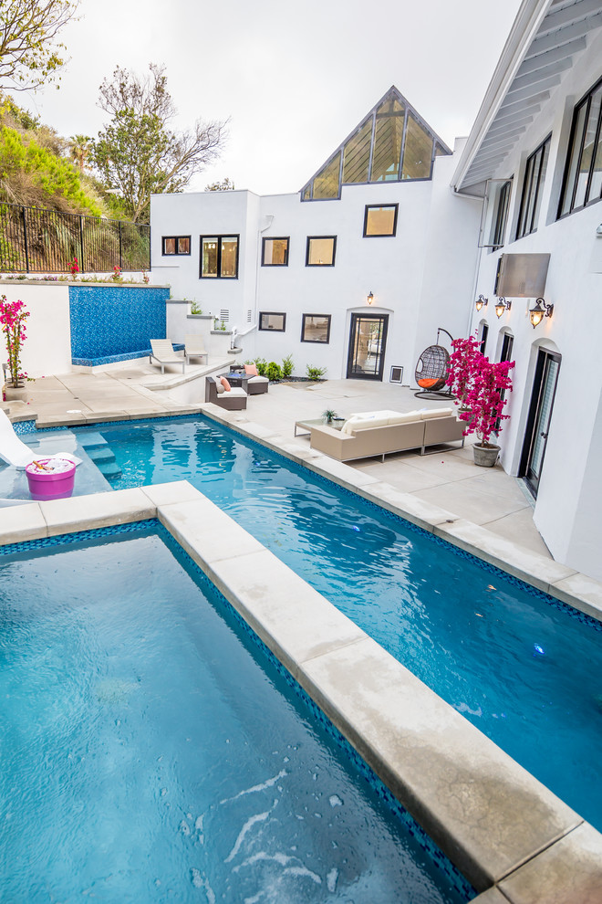 Example of a large minimalist backyard stamped concrete and rectangular lap hot tub design in Orange County