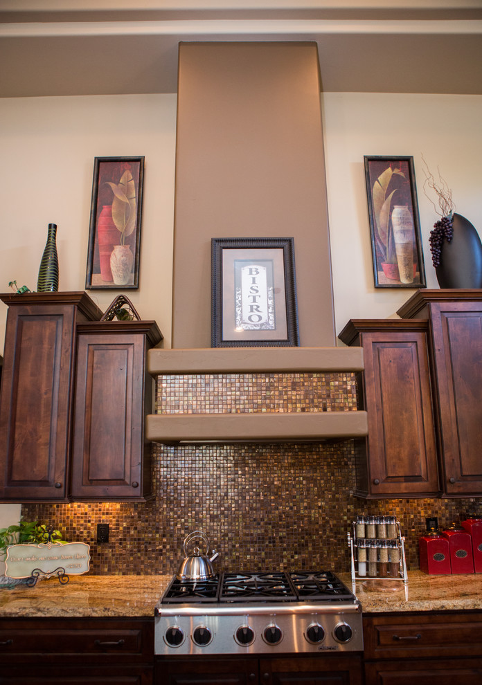 Large transitional u-shaped eat-in kitchen photo in Phoenix with raised-panel cabinets, dark wood cabinets, granite countertops, beige backsplash, glass tile backsplash, stainless steel appliances and an island