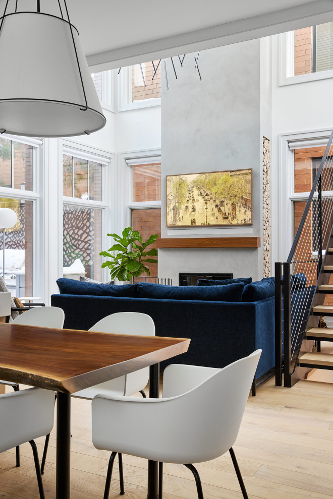 Источник вдохновения для домашнего уюта: открытая гостиная комната в стиле модернизм с белыми стенами, светлым паркетным полом, стандартным камином, фасадом камина из бетона, скрытым телевизором и сводчатым потолком