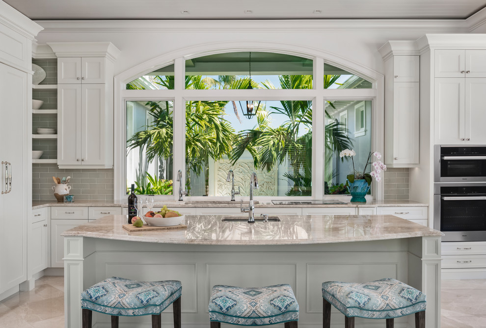 Example of a large transitional l-shaped travertine floor and beige floor eat-in kitchen design with an undermount sink, shaker cabinets, white cabinets, quartzite countertops, green backsplash, ceramic backsplash, paneled appliances, an island and beige countertops