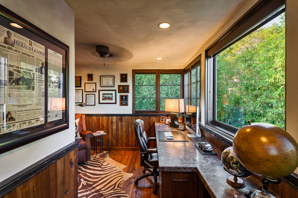 This is an example of a mediterranean home office in Santa Barbara with beige walls, dark hardwood floors and a built-in desk.