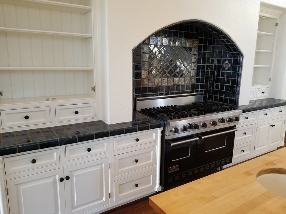 Inspiration for a large transitional u-shaped medium tone wood floor and brown floor enclosed kitchen remodel in Los Angeles with a farmhouse sink, raised-panel cabinets, white cabinets, wood countertops, black backsplash, ceramic backsplash, paneled appliances, an island and brown countertops