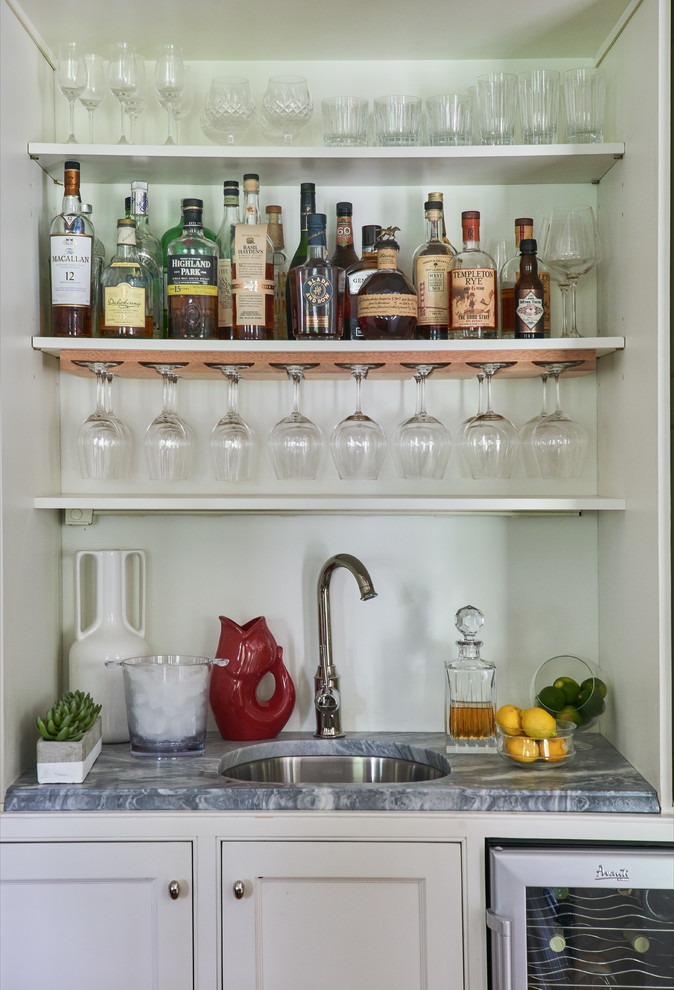 Transitional single-wall wet bar in New York with an undermount sink, white splashback, grey benchtop, flat-panel cabinets, white cabinets and marble benchtops.