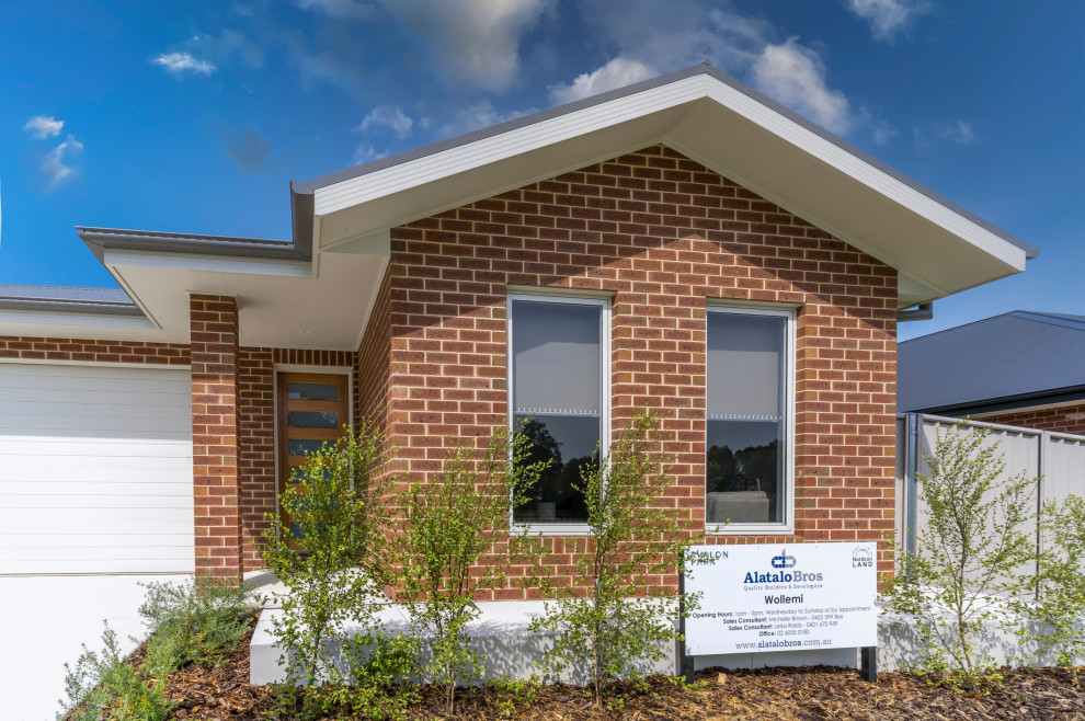 Photo of a mid-sized contemporary one-storey brick house exterior with a gable roof, a metal roof and a grey roof.