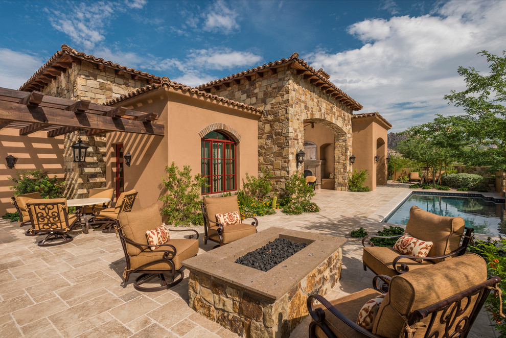 This is an example of an expansive traditional backyard patio in Phoenix with natural stone pavers and a roof extension.